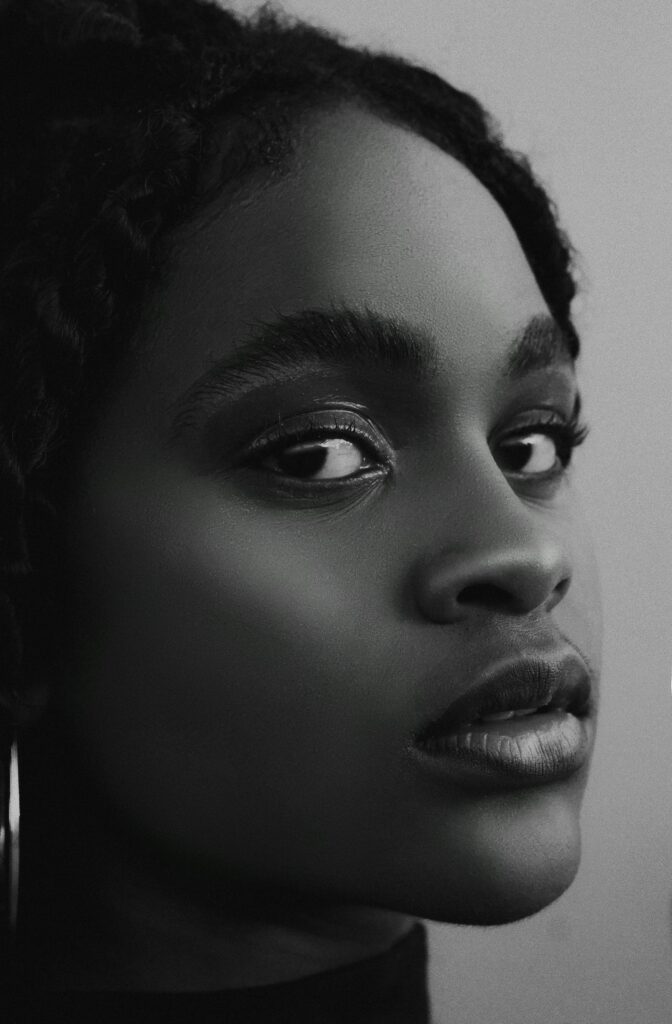 Black and white close-up portrait of a young woman with a focus on beauty and emotion.
